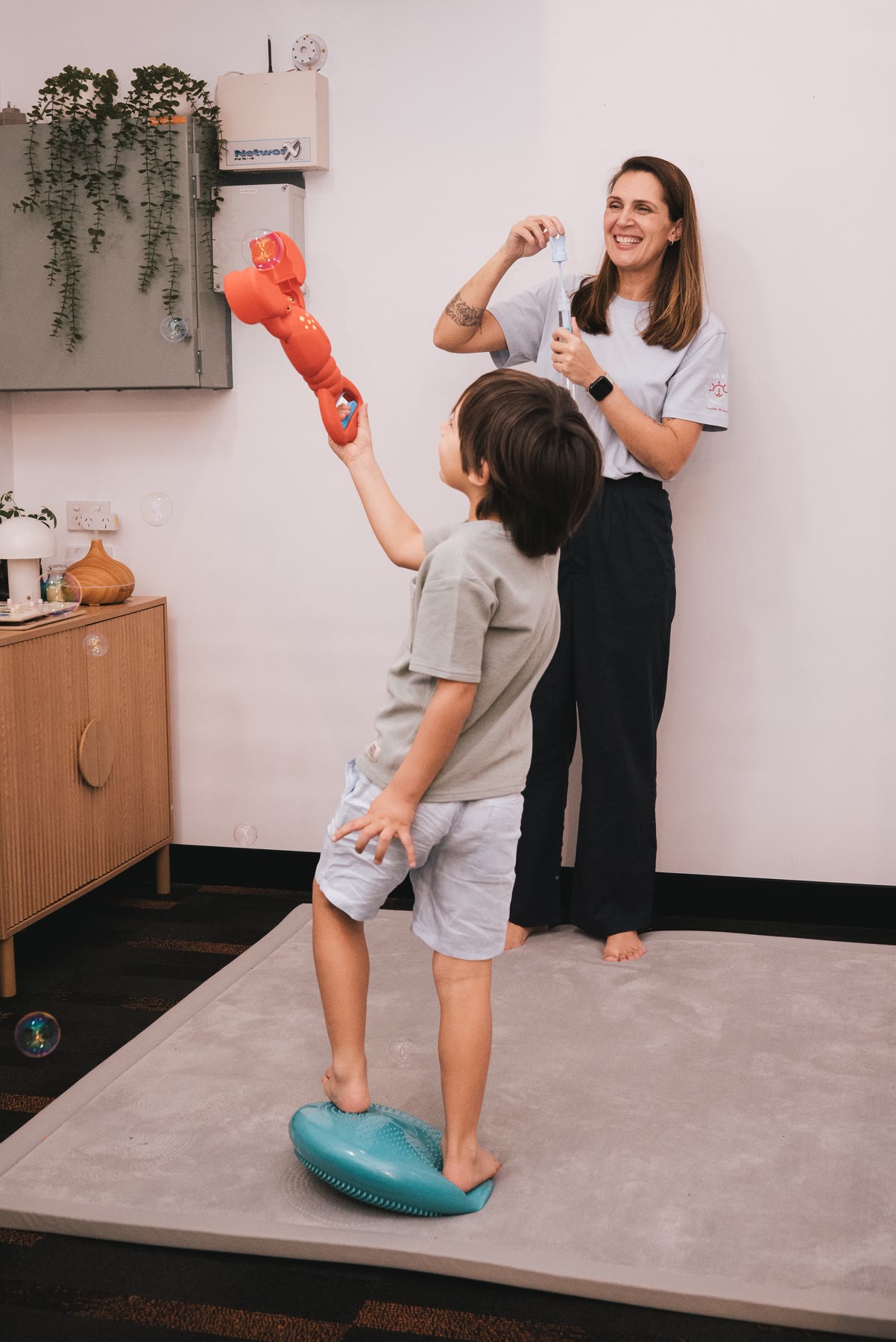 Amanda playing a sensory balance game with a child in the therapy room