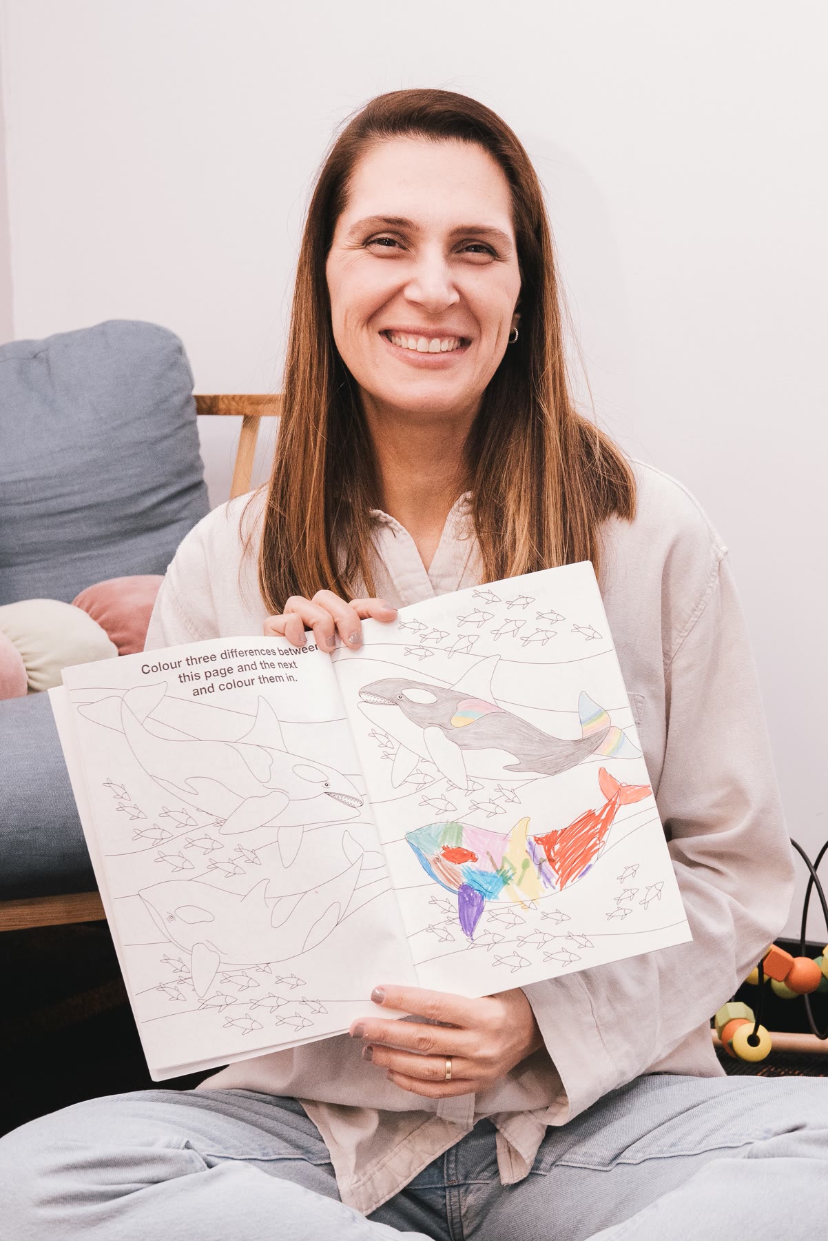 Amanda smiling while holding a coloured-in activity book with a child