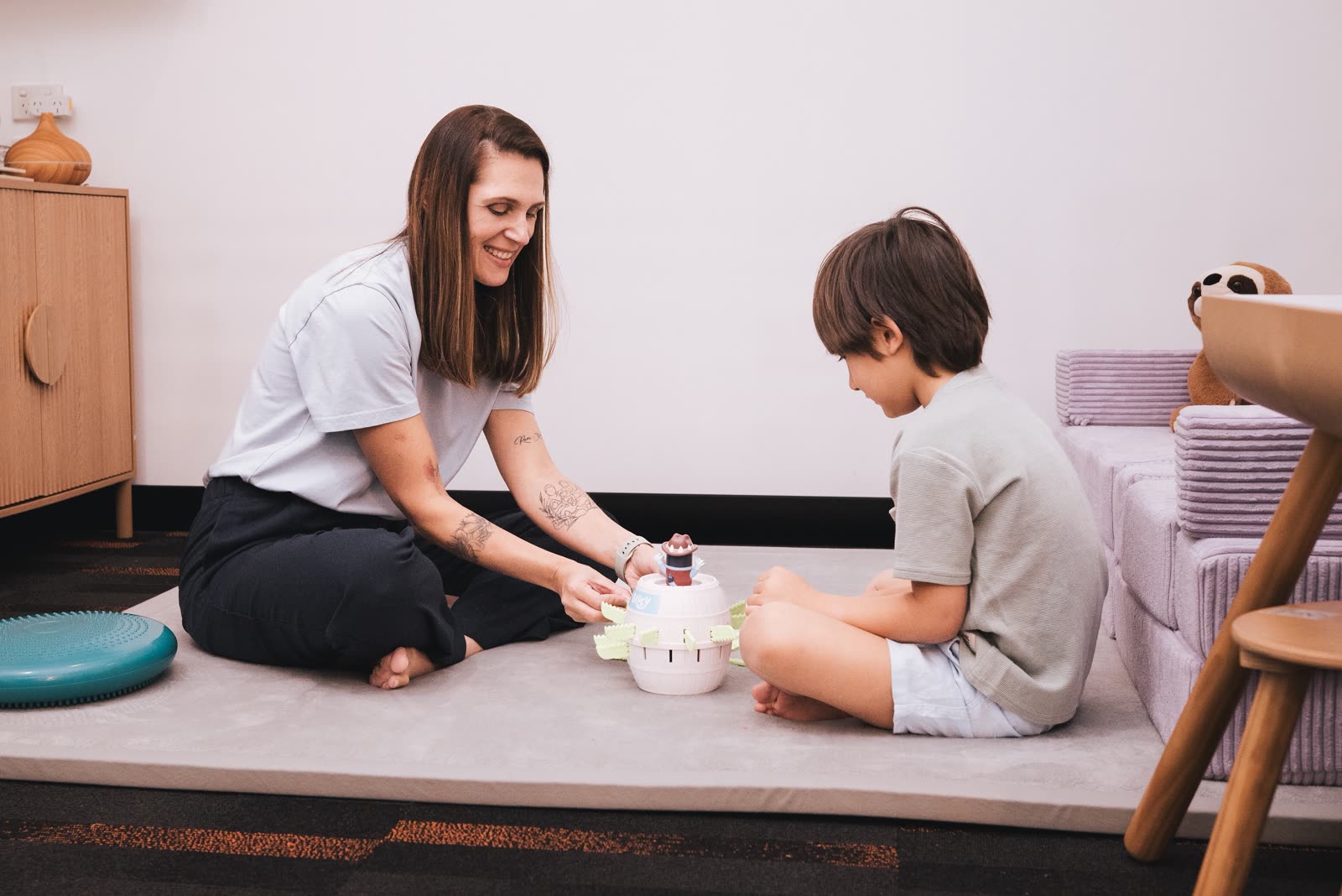 Amanda and a child playing with a spinning toy on the floor mat